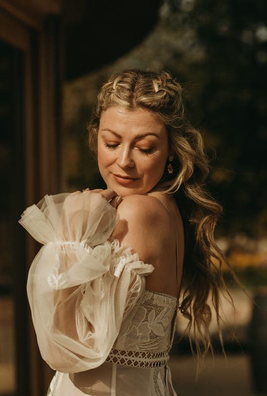 A bride with braided hair and softly defined bridal make-up, looking down